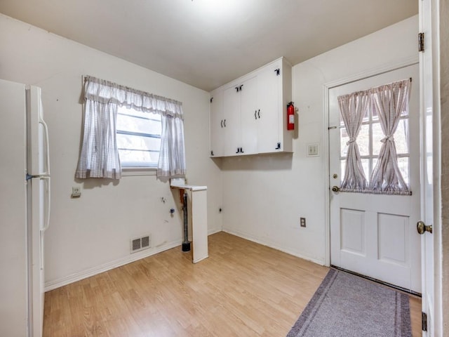 foyer with light wood-type flooring, visible vents, and baseboards