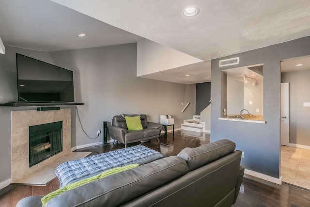 living room with lofted ceiling, dark hardwood / wood-style flooring, and a tile fireplace