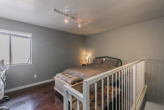 bedroom with dark hardwood / wood-style flooring and rail lighting