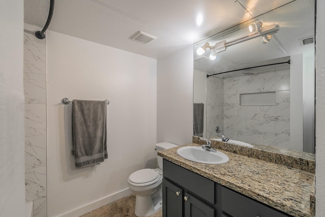 bathroom featuring vanity, toilet, and a tile shower