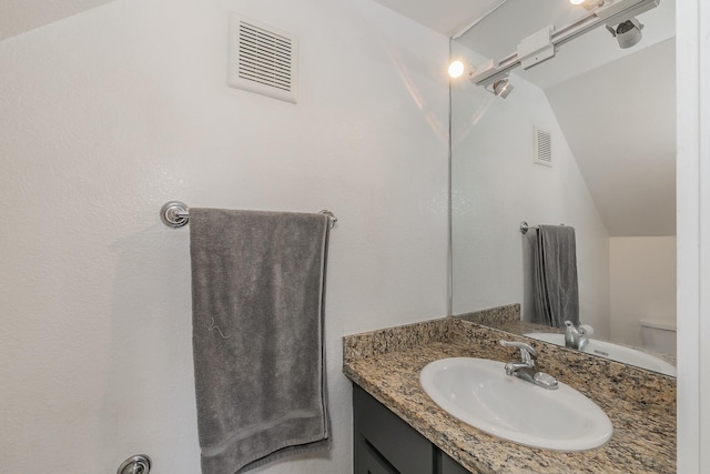 bathroom with vanity, toilet, and vaulted ceiling