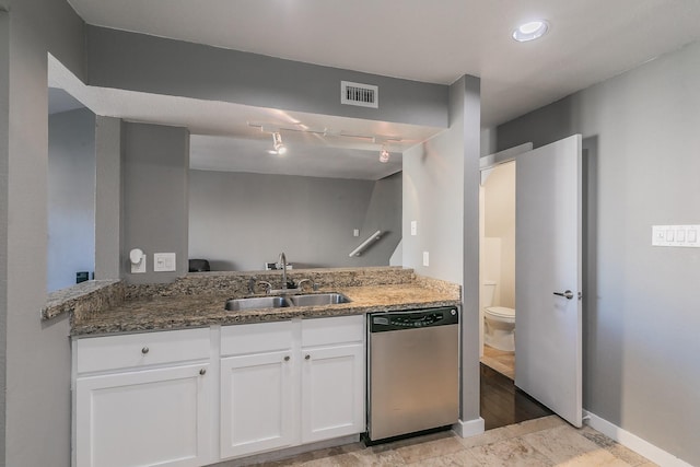 kitchen with dishwasher, dark stone counters, sink, kitchen peninsula, and white cabinetry