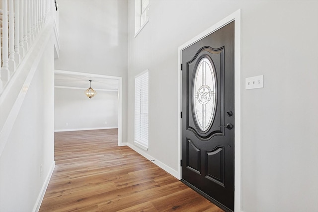 entryway with a towering ceiling and light wood-type flooring