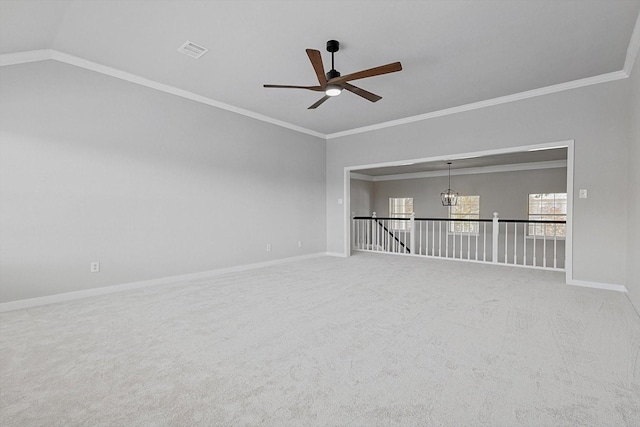 carpeted spare room featuring ceiling fan with notable chandelier, ornamental molding, and vaulted ceiling