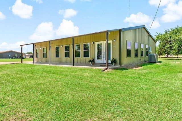 rear view of property featuring a yard, a patio area, and central air condition unit