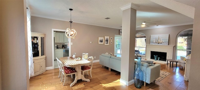 dining area featuring a textured ceiling, light hardwood / wood-style flooring, and crown molding