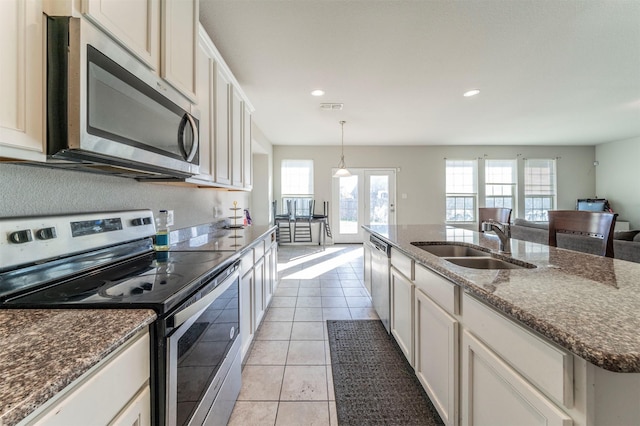 kitchen featuring sink, hanging light fixtures, a kitchen island with sink, light tile patterned floors, and appliances with stainless steel finishes