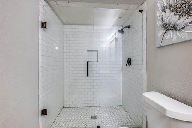 bathroom featuring toilet and a shower with door