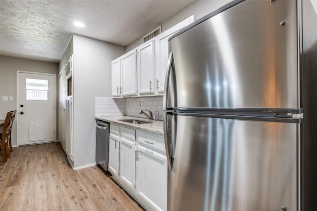 kitchen with light stone countertops, sink, stainless steel appliances, decorative backsplash, and white cabinets