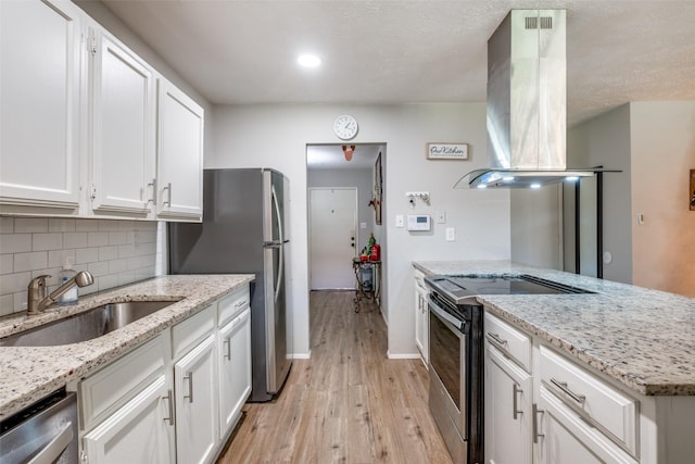 kitchen with island exhaust hood, light stone counters, stainless steel appliances, sink, and white cabinetry