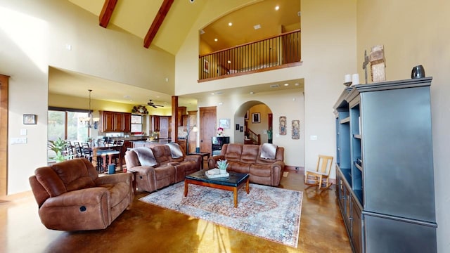 living room with beam ceiling, a chandelier, concrete floors, and a high ceiling