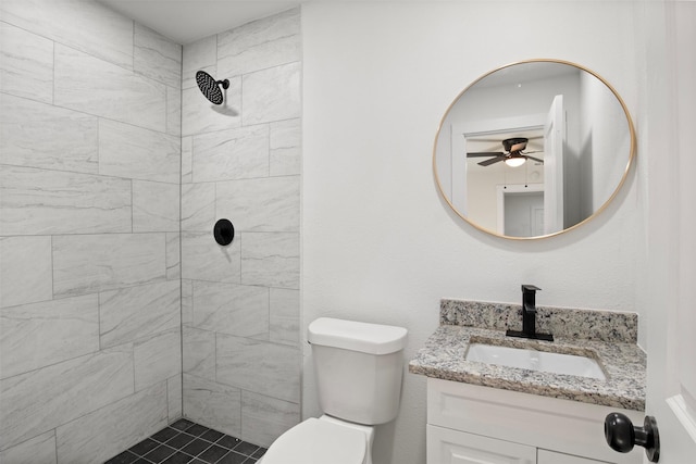 bathroom with ceiling fan, vanity, toilet, and a tile shower