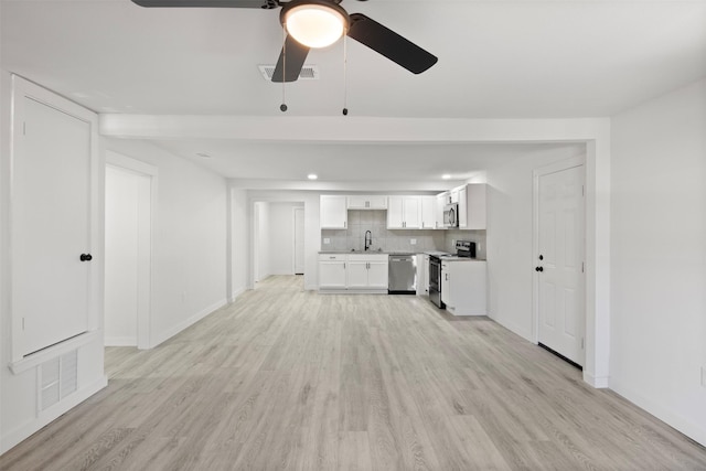 unfurnished living room with light wood-type flooring, ceiling fan, and sink