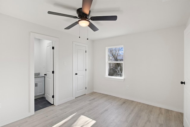 unfurnished bedroom featuring a closet, ensuite bathroom, light hardwood / wood-style flooring, and ceiling fan