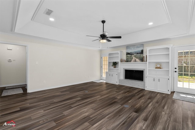 unfurnished living room with dark hardwood / wood-style flooring, ceiling fan, a raised ceiling, and a fireplace