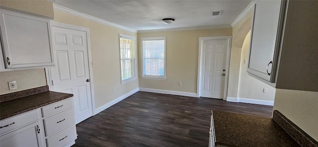 unfurnished dining area with dark wood-type flooring, a textured ceiling, and ornamental molding