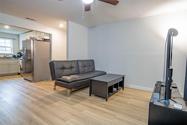 living room featuring light hardwood / wood-style flooring, ceiling fan, and sink