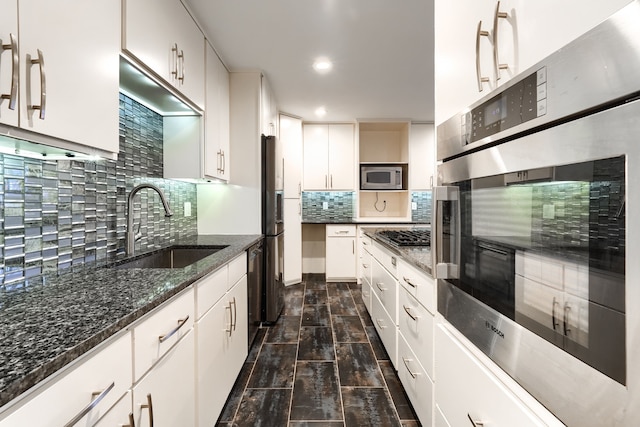 kitchen featuring tasteful backsplash, appliances with stainless steel finishes, sink, and white cabinets