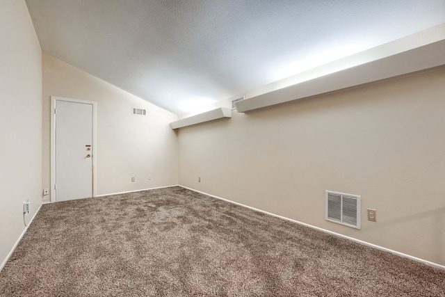 interior space featuring vaulted ceiling, carpet floors, and a textured ceiling