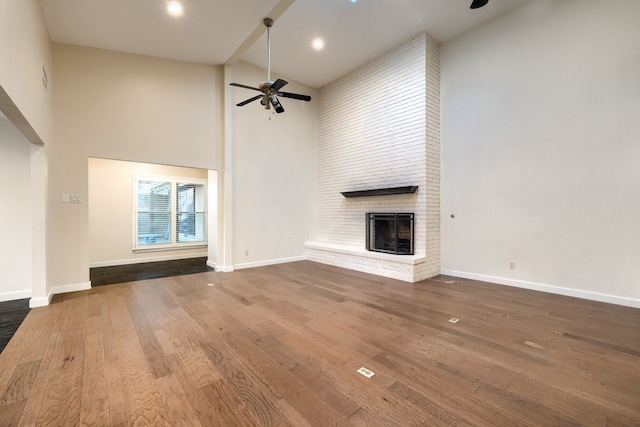 unfurnished living room with ceiling fan, wood-type flooring, a fireplace, and high vaulted ceiling