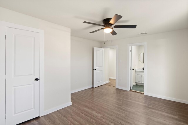 unfurnished bedroom with ceiling fan, ensuite bathroom, and hardwood / wood-style floors