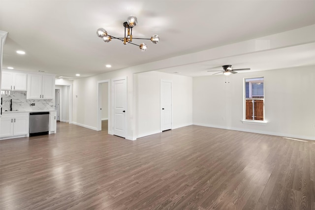 unfurnished living room with sink, ceiling fan with notable chandelier, and dark hardwood / wood-style floors