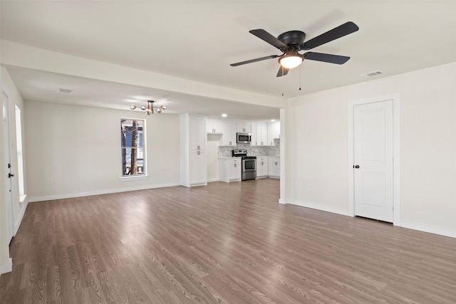 unfurnished living room with hardwood / wood-style flooring and ceiling fan with notable chandelier