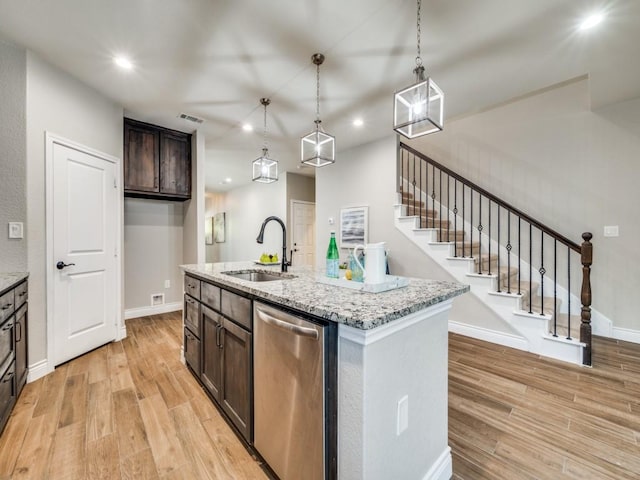 kitchen featuring dishwasher, sink, light stone countertops, a center island with sink, and light hardwood / wood-style flooring