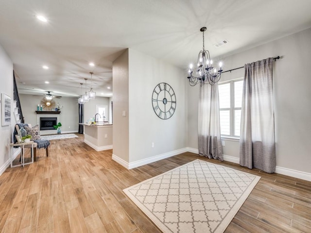 interior space with ceiling fan with notable chandelier and light hardwood / wood-style flooring