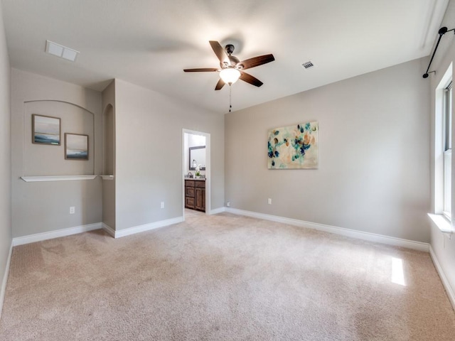 unfurnished bedroom with ceiling fan, ensuite bath, and light carpet