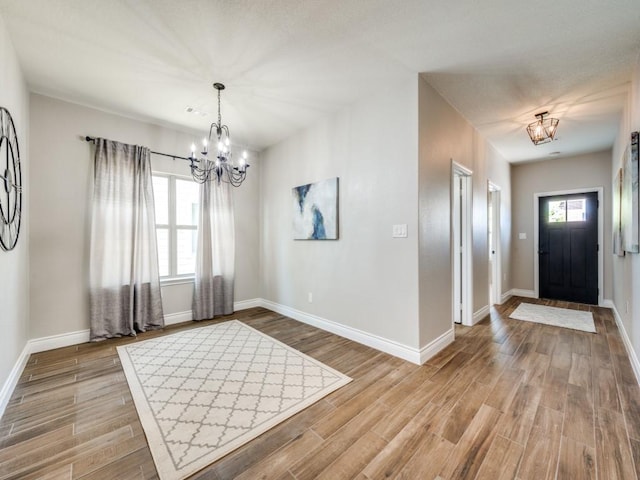 foyer with a wealth of natural light, light hardwood / wood-style floors, and a chandelier