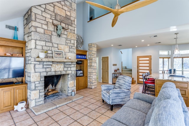 living room with a fireplace, light tile patterned floors, and a towering ceiling