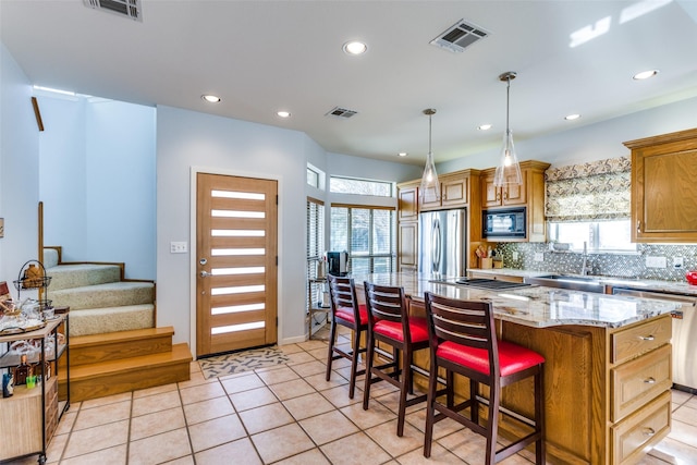 kitchen with a kitchen island, light tile patterned flooring, a healthy amount of sunlight, and stainless steel appliances