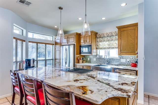 kitchen with pendant lighting, a kitchen breakfast bar, a spacious island, light stone countertops, and appliances with stainless steel finishes