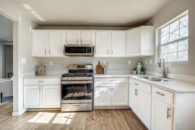 kitchen with white cabinetry, sink, light hardwood / wood-style floors, and appliances with stainless steel finishes