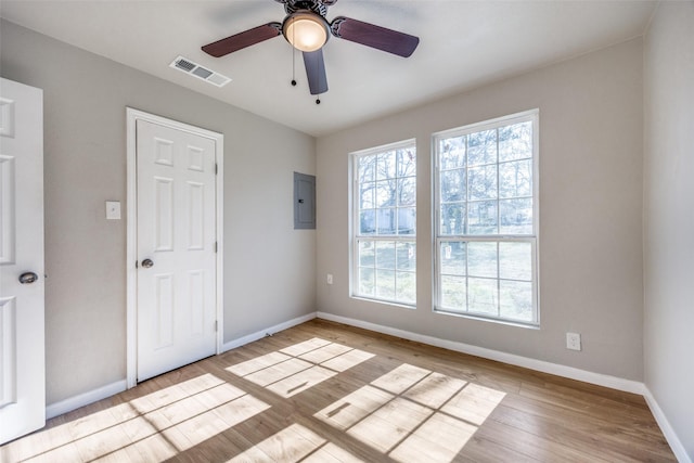 spare room with electric panel, ceiling fan, and light hardwood / wood-style floors