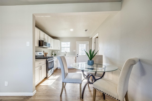 dining space with sink and light wood-type flooring