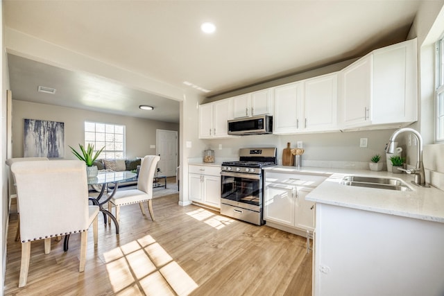 kitchen featuring light stone countertops, sink, stainless steel appliances, light hardwood / wood-style flooring, and white cabinets