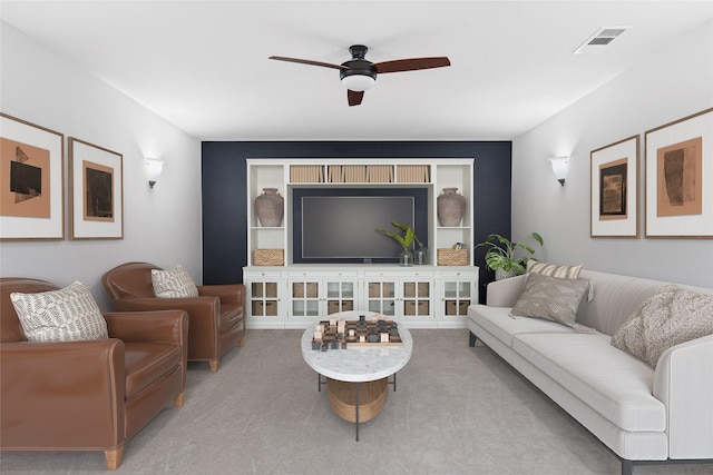 living room featuring a ceiling fan, visible vents, and light carpet