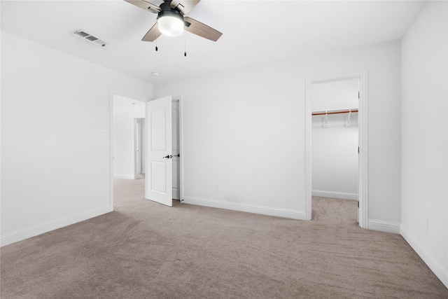 unfurnished bedroom with baseboards, a spacious closet, visible vents, and light colored carpet