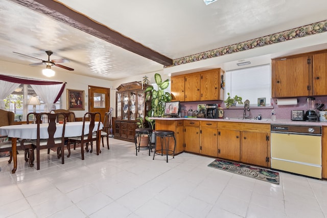 kitchen featuring ceiling fan, sink, beamed ceiling, kitchen peninsula, and dishwashing machine