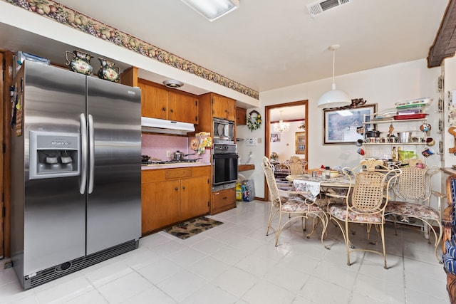 kitchen featuring an inviting chandelier, hanging light fixtures, decorative backsplash, light tile patterned floors, and stainless steel appliances