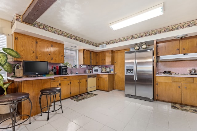 kitchen featuring a breakfast bar, white appliances, sink, a healthy amount of sunlight, and kitchen peninsula