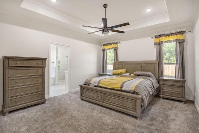 bedroom featuring ensuite bathroom, ornamental molding, light colored carpet, a raised ceiling, and ceiling fan