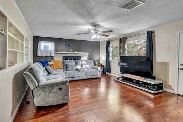 living room featuring ceiling fan, dark wood-type flooring, a textured ceiling, and built in shelves