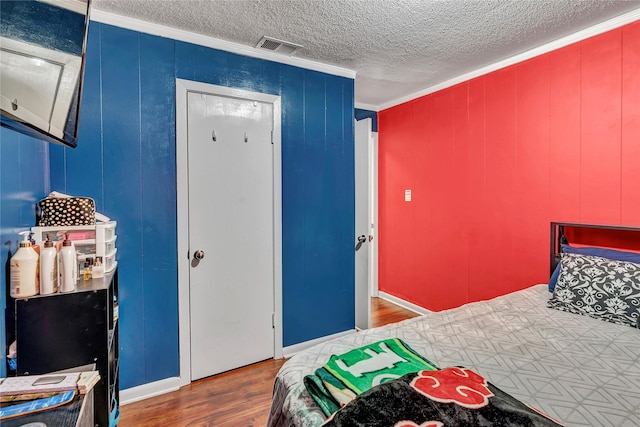 bedroom featuring ornamental molding, hardwood / wood-style floors, and a textured ceiling