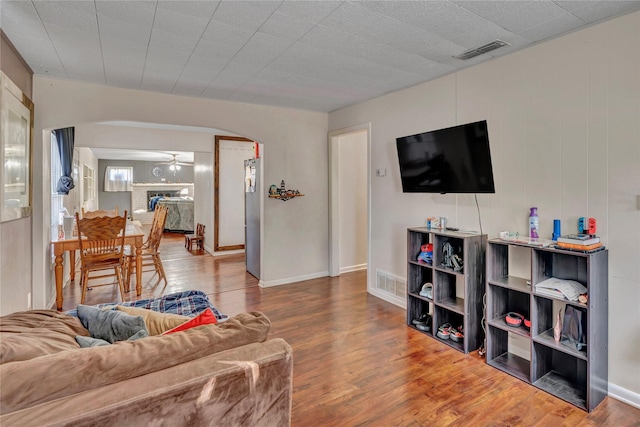 living room featuring ceiling fan, hardwood / wood-style floors, and a brick fireplace