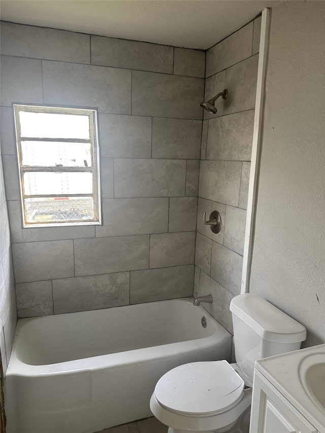 full bathroom featuring tiled shower / bath, vanity, and toilet