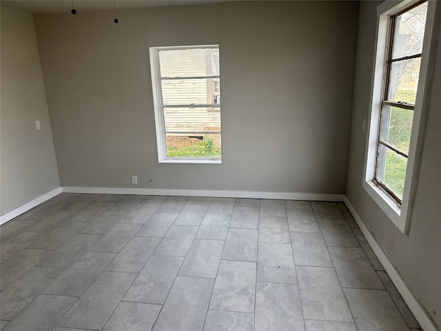 empty room with a healthy amount of sunlight and light tile patterned flooring