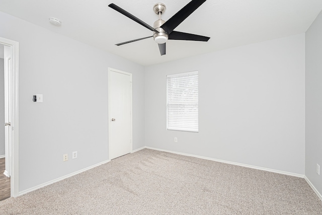 carpeted spare room featuring ceiling fan